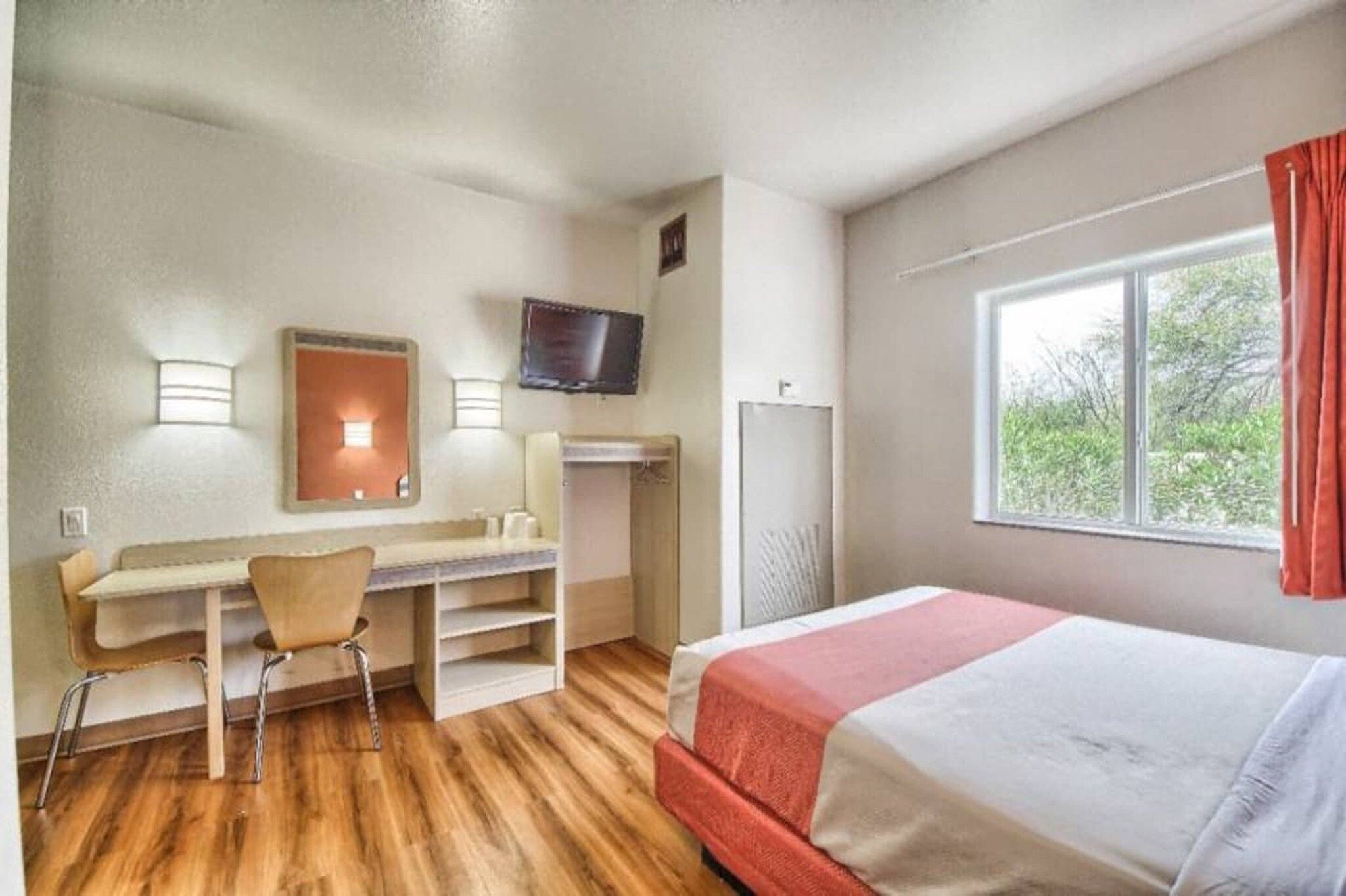 Hotellihuone, jossa on sänky, työpöytä, tuoli, televisio ja ikkuna.