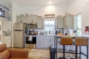 A modern kitchen with stainless steel appliances, a dining area with a table and chairs, and a view of the outdoors through a window. - Screened Porch w/ Fireplace! Copperhill Tiny Home (Copperhill)