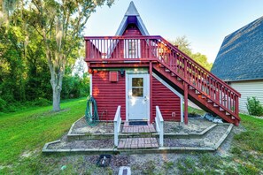 A red wooden structure with a white door, a small porch, and a staircase leading to a roof. - Swing, Swim & Play: 'Lazy Daze' w/ Pool Access (Clermont)