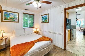 A bedroom with a bed, a nightstand, a window with blinds, a ceiling fan, and a view of the kitchen. - Swing, Swim & Play: 'Lazy Daze' w/ Pool Access (Clermont)