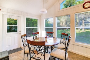 A sunroom with a round table and six chairs, large windows, and a clock on the wall. - Swing, Swim & Play: 'Lazy Daze' w/ Pool Access (Clermont)