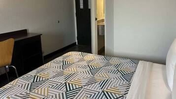 A hotel room with a bed, a desk, and a chair.