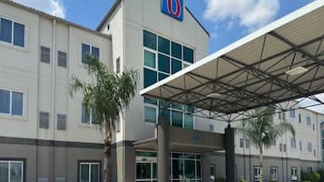 A 6-star hotel with a covered entrance, multiple windows, and a palm tree.