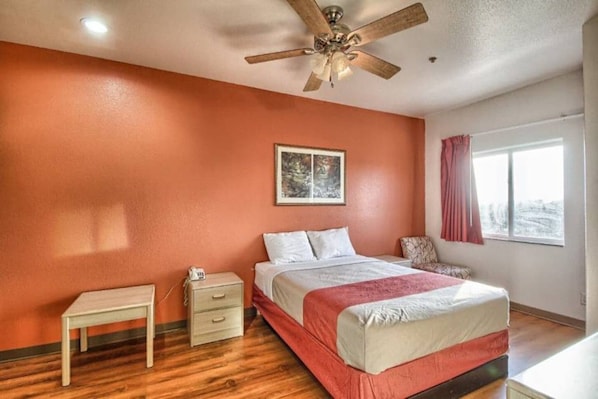 Une chambre à coucher avec un lit, une table de chevet, une commode et un ventilateur de plafond.