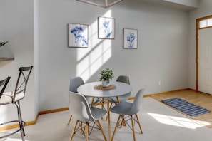 Ein moderner Essbereich mit einem runden Tisch, grauen Stühlen und gerahmten Kunstwerken an der Wand.