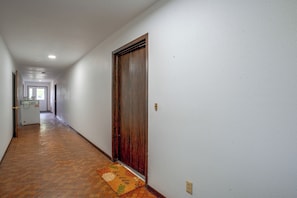 Ein Flur mit Holztür, Fußmatte und Lichtschalter an der Wand.
