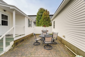 Un espace patio avec une table ronde et des chaises, un barbecue et un petit arbre.