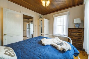 A bedroom with a bed, a dresser, a window with curtains, and a door leading to a kitchen. - Steps to Shore! Old Orchard Beach Gem w/ Patio (Old Orchard Beach)