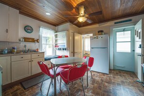 A kitchen with a dining table, red chairs, a ceiling fan, and a refrigerator. - Steps to Shore! Old Orchard Beach Gem w/ Patio (Old Orchard Beach)