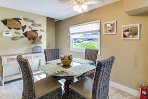 A dining area with wicker furniture, a glass-top table, and a ceiling fan. - Sun-Kissed Cottage: Lake Access, 14 Mi to Disney (Clermont)