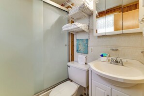 Un baño con inodoro, lavamanos y perchero para toallas.