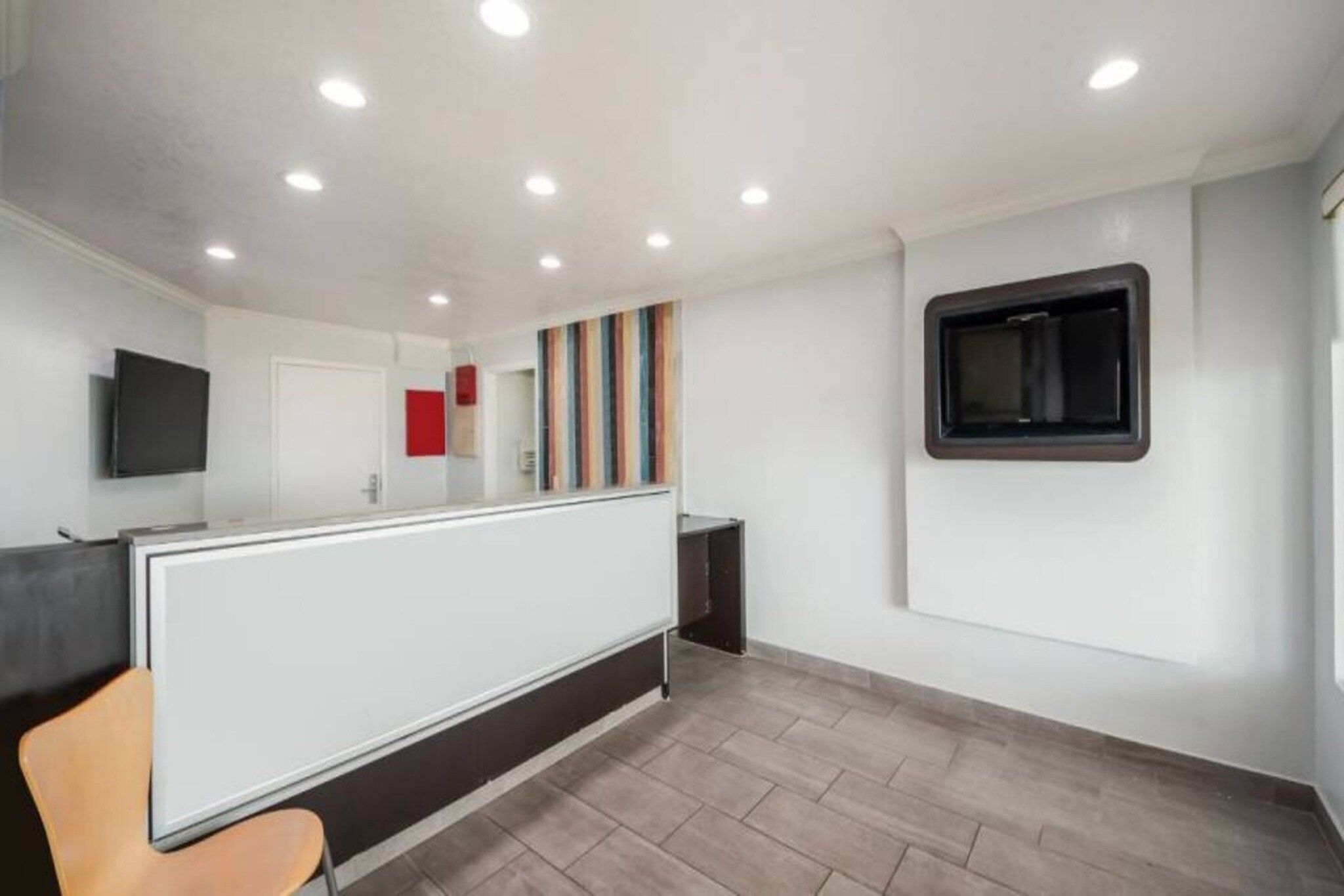 Ein modernes Interieur mit einer Rezeption, einem Flachbildfernseher und einem Fenster mit Jalousien.