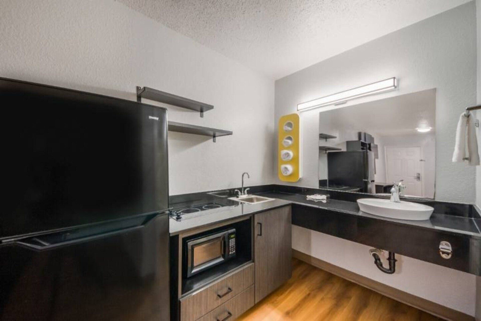 Eine moderne Küche mit einem schwarzen Kühlschrank, einer Mikrowelle und einem Spülbecken.
