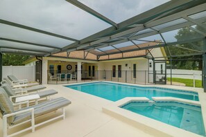 Une piscine extérieure couverte, dotée de chaises longues et d’un espace patio.