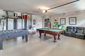A room with a pool table, a foosball table, a sofa, and a billiards table. - Spacious 4BR w/ South-Facing Pool/Spa: Disney 11Mi (Clermont)