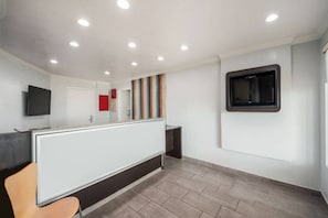 A modern interior with a reception desk, a flat-screen TV, and a window with blinds. - 1 King Bed | Smoking, Kitchen (Laredo)