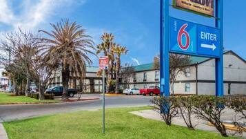 A motel with a large blue sign indicating room number 6 and an arrow pointing to the entrance.