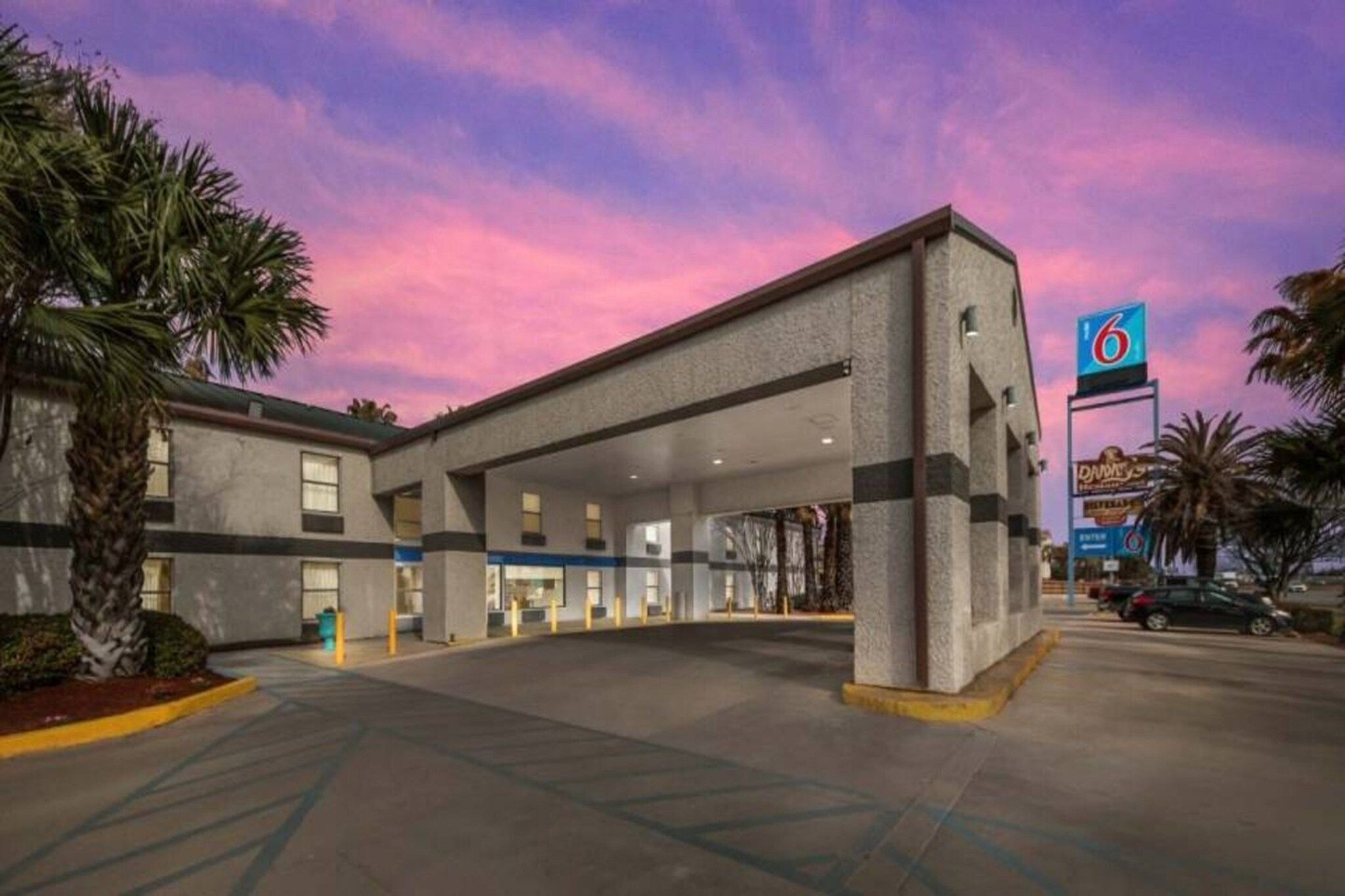 Un hotel con un amplio estacionamiento, un letrero de clasificación de 6 estrellas y un edificio con muchas ventanas.