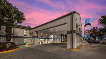 Un hotel con un amplio estacionamiento, un letrero de clasificación de 6 estrellas y un edificio con muchas ventanas.