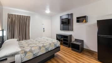 A modern hotel room with a bed, a desk, a television, and a wardrobe.