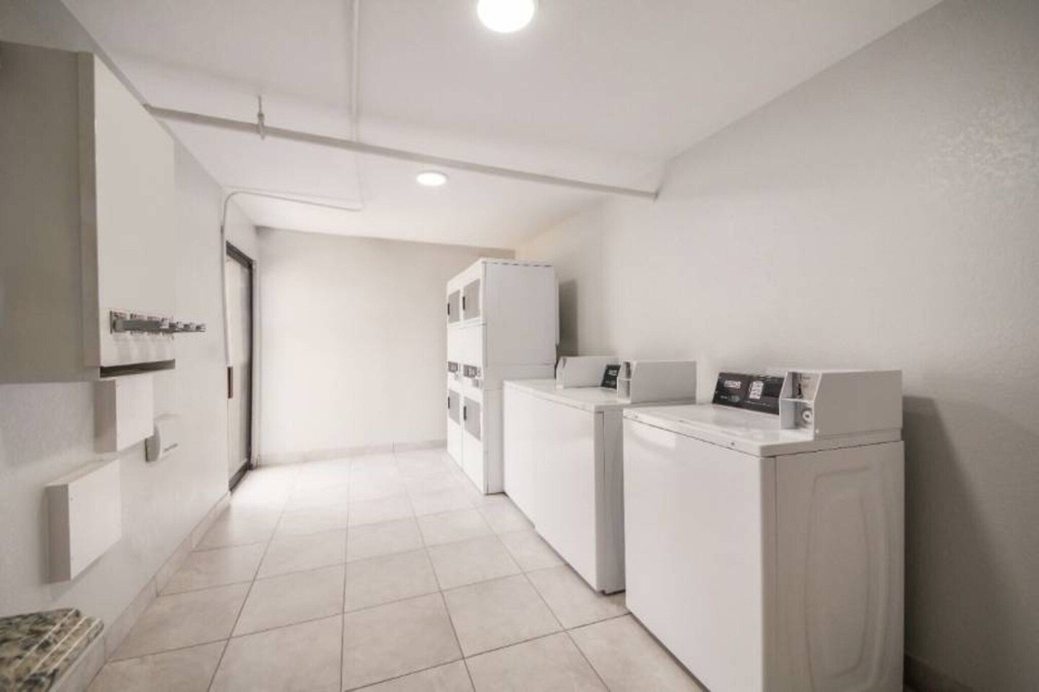 Un cuarto de lavado con lavadora, secadora y armarios apilados.