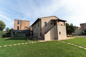 A modern building with a brick facade, a flat roof, and a small garden area with a pathway. - Agriturismo Borgo Re (Deruta)