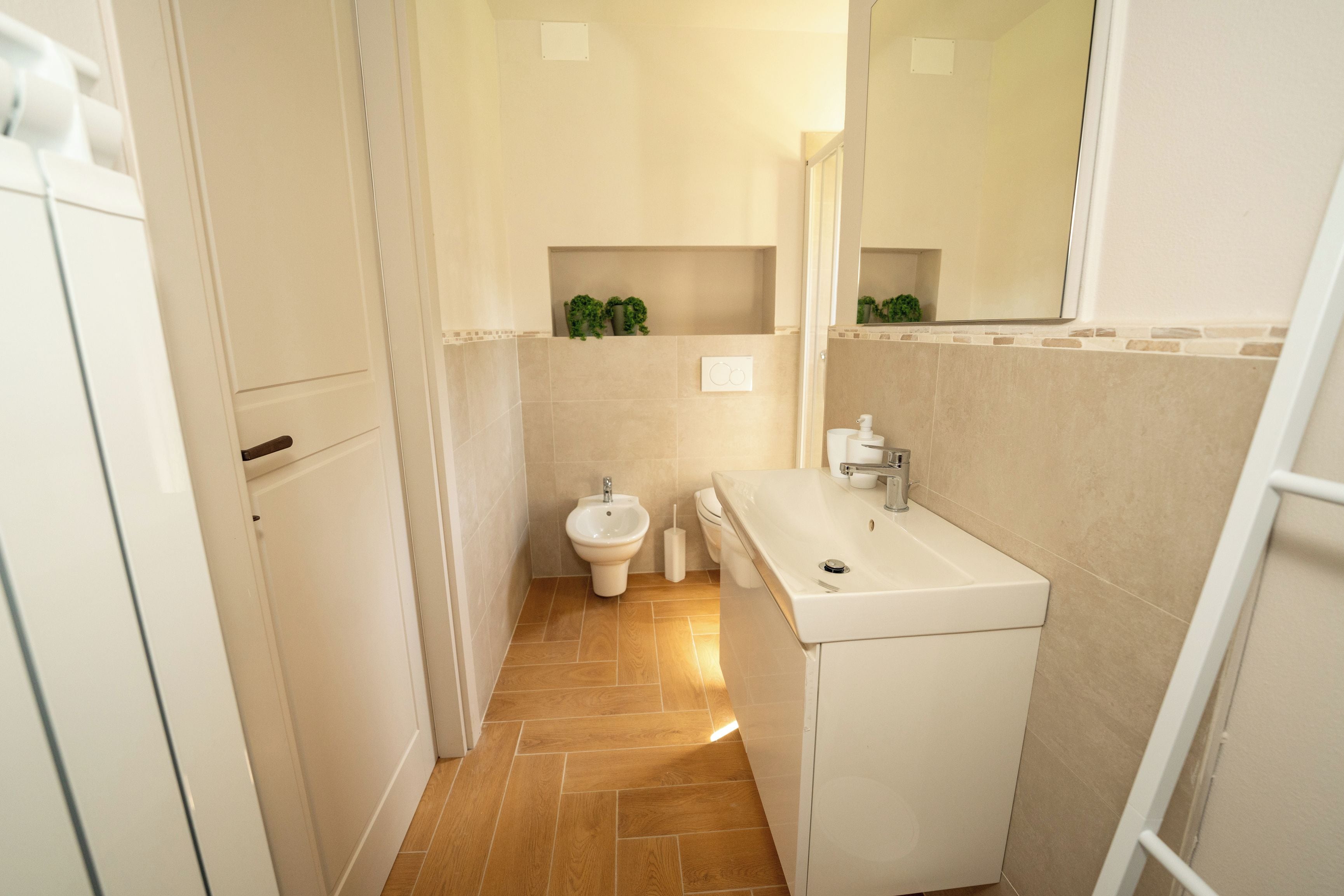 A compact bathroom with a toilet, bidet, and sink.