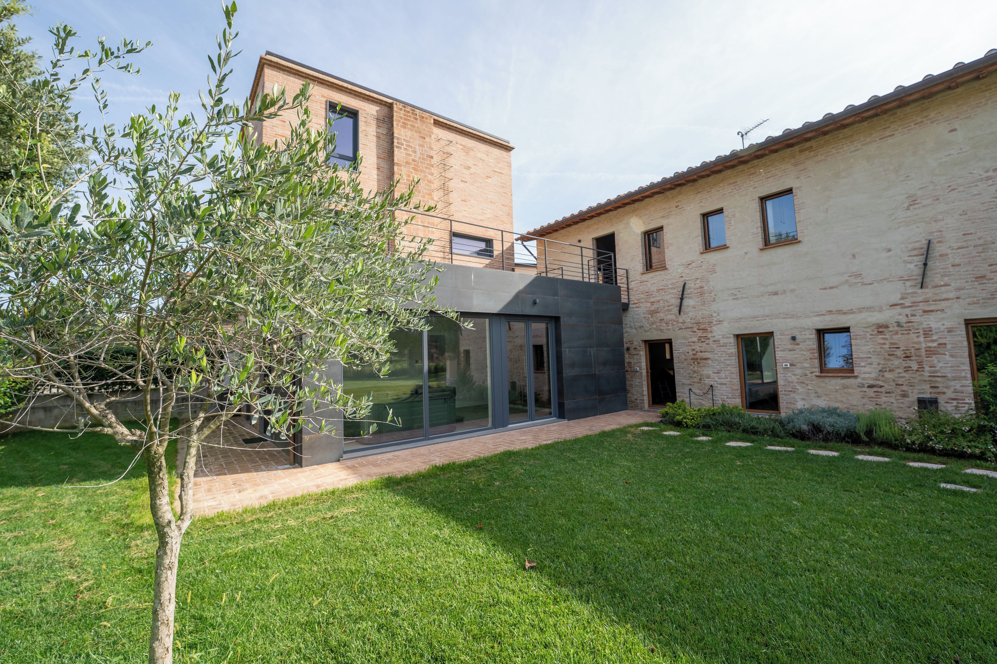 A modern building with a glass facade, a brick exterior, and a well-maintained lawn.
