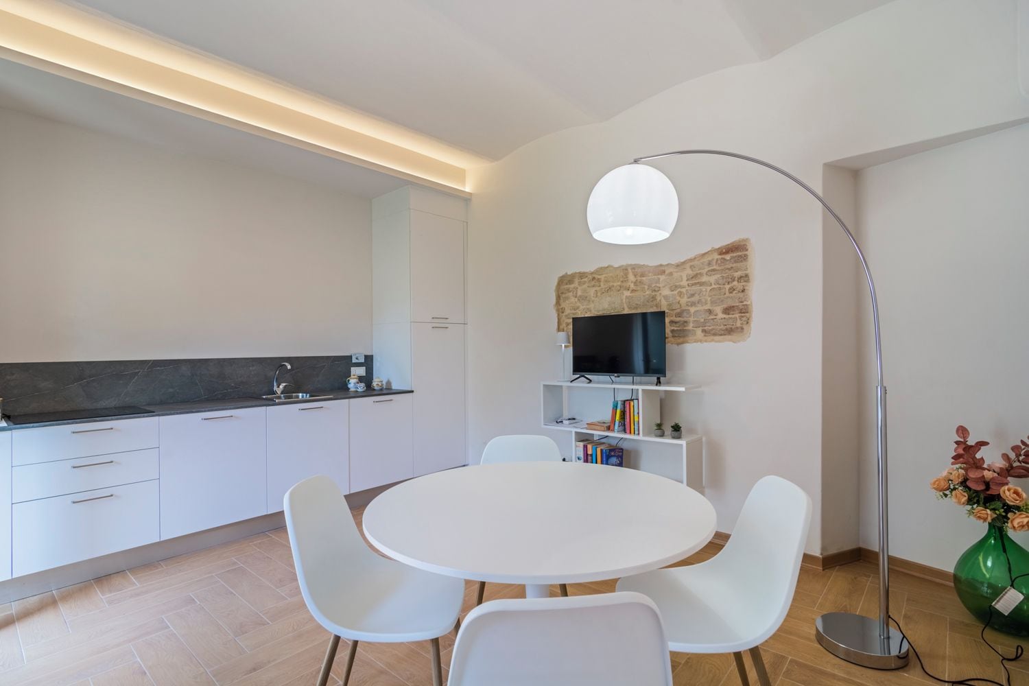 Een moderne keuken met witte kasten, een zwart aanrecht en een ingebouwde televisie.