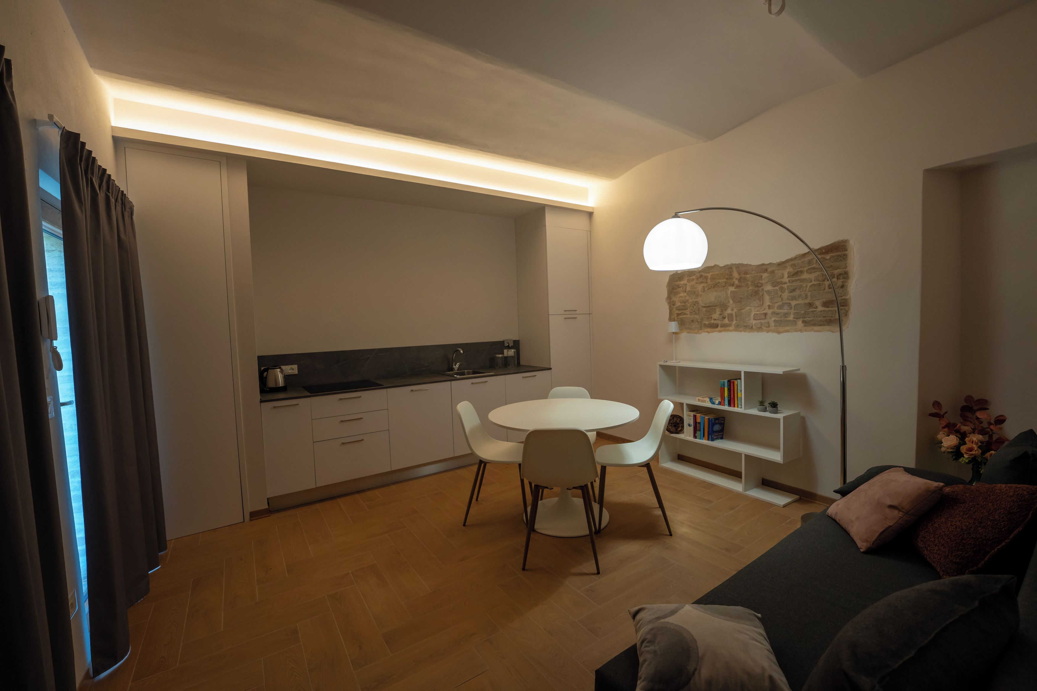A modern living room with a dining area, a sofa, a coffee table, and a bookshelf.