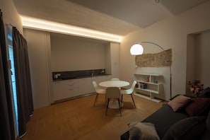 Una sala de estar moderna con comedor, un sofá, una mesa de centro y una estantería.