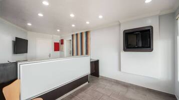 A modern interior with a reception desk, a flat-screen TV, and a window with blinds.