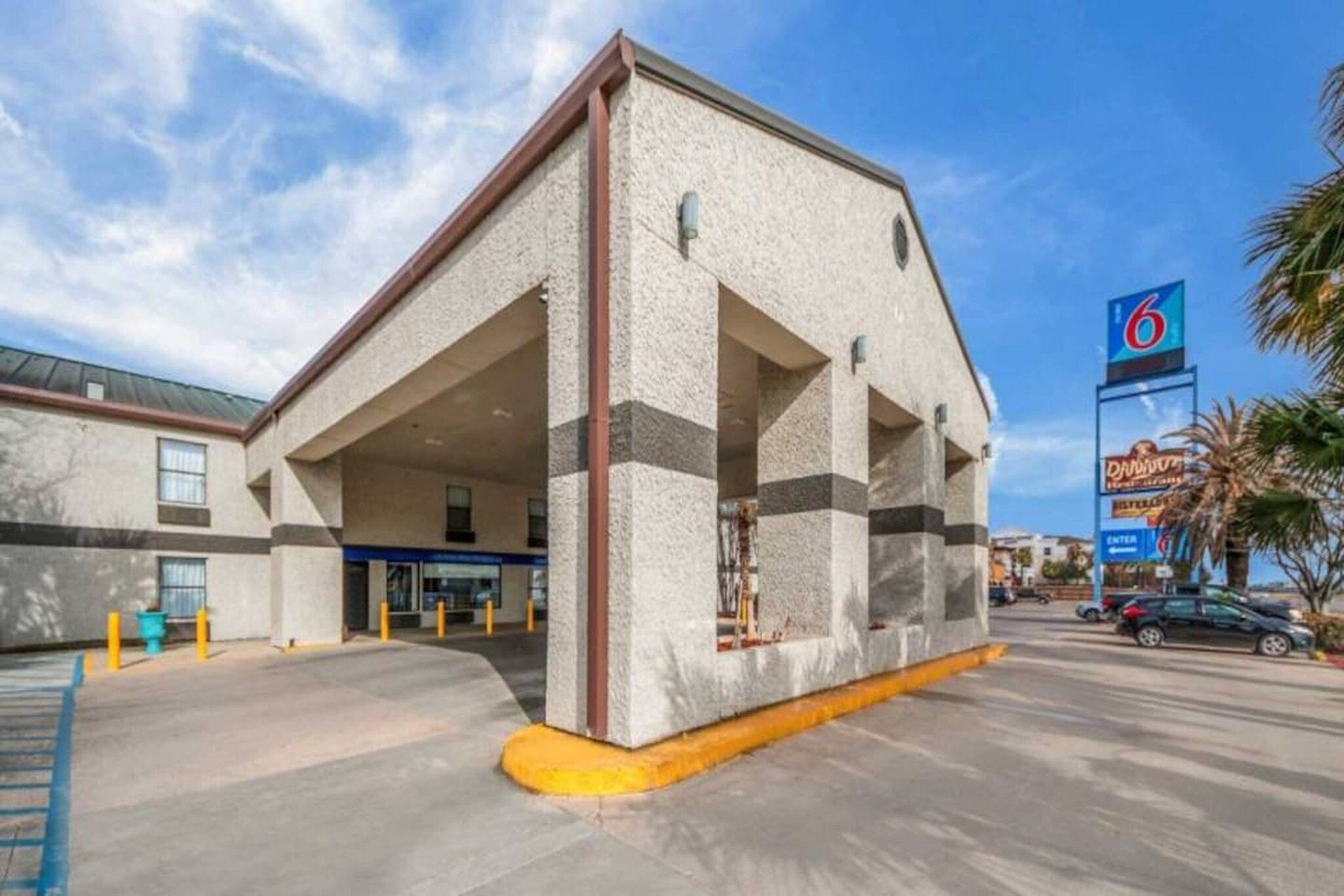 Un edificio con un amplio estacionamiento, un letrero de hotel de 6 estrellas y cielo despejado.
