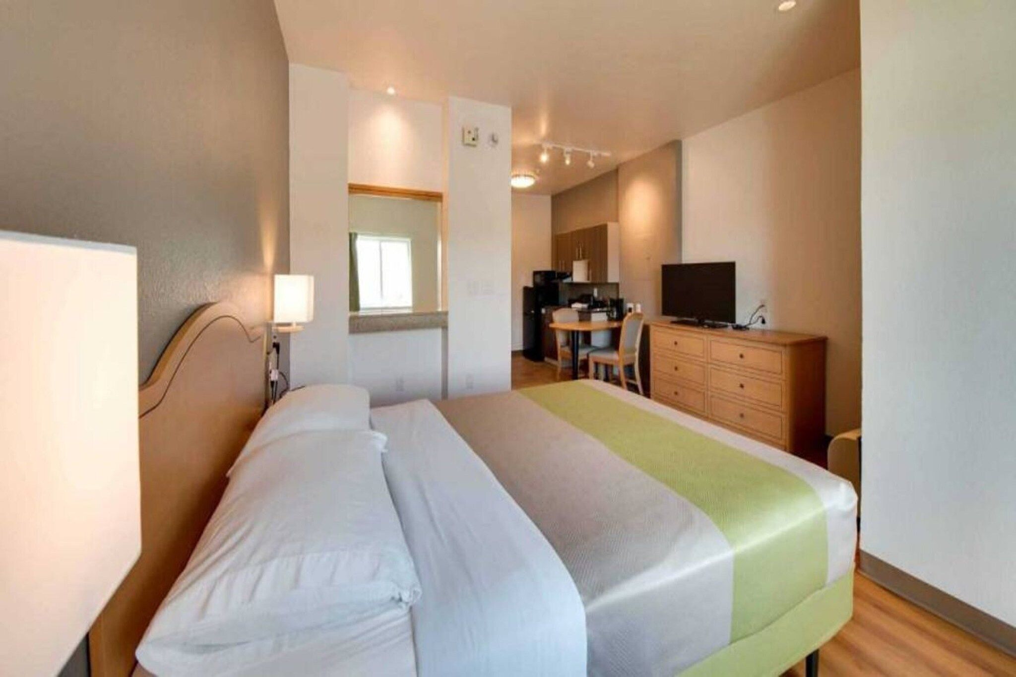 A hotel room with a bed, a desk, a television, and a mirror.