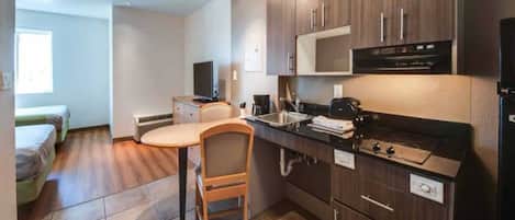 A compact kitchen with a dining area, a bed, and a window.
