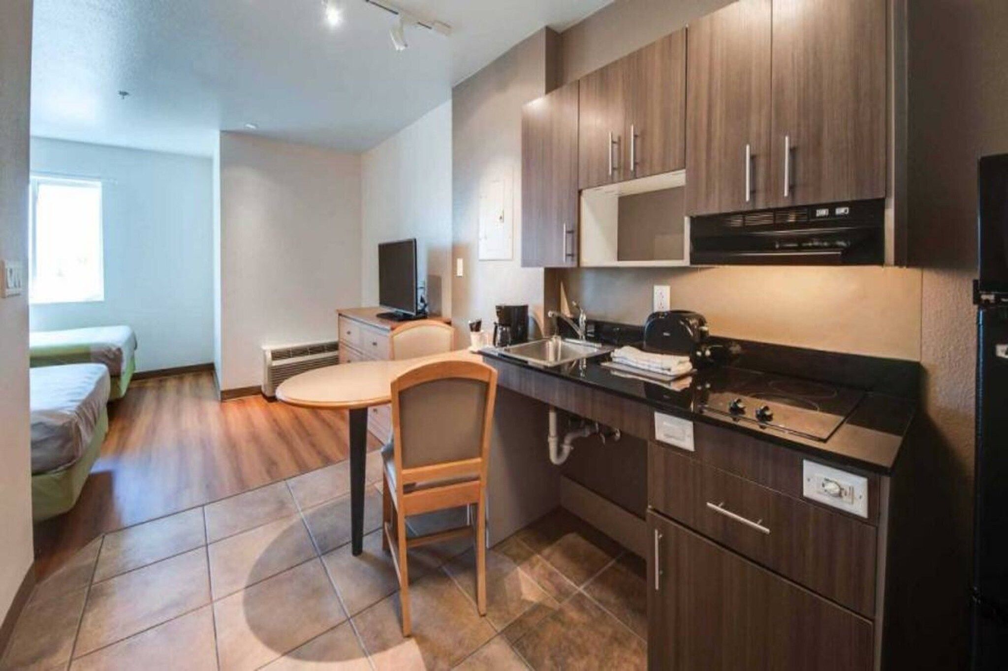 A compact kitchen with a dining area, a bed, and a window.
