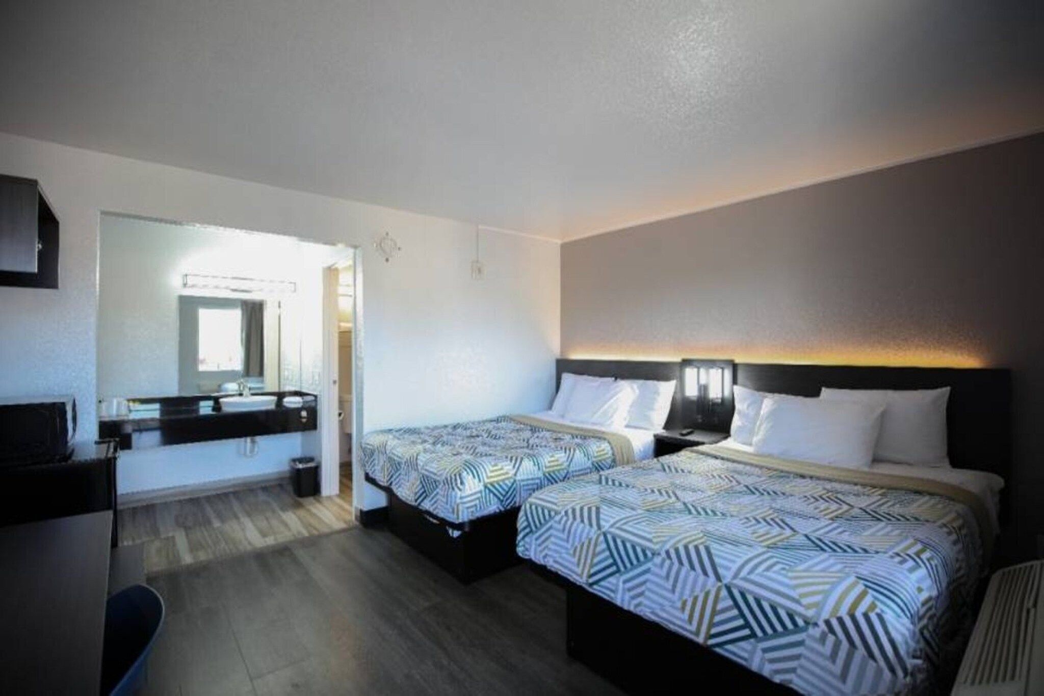 Ett hotellrum med två sängar, ett skrivbord och en spegel.