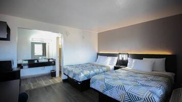 Ett hotellrum med två sängar, ett skrivbord och en spegel.