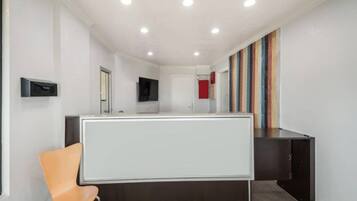 A modern interior with a reception desk, a chair, a flat-screen TV, and a colorful striped wall.