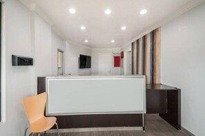 Un intérieur moderne comprenant un comptoir d’accueil, un fauteuil, un téléviseur à écran plat et un mur rayé aux couleurs vives.