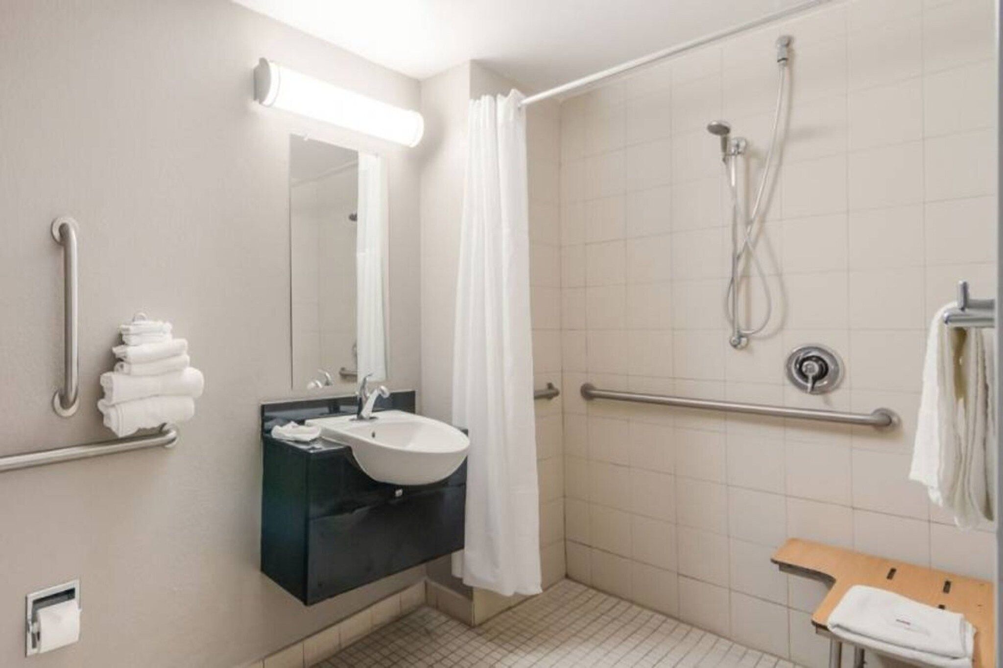 Ein Badezimmer mit Dusche, Waschbecken, Spiegel und Handtuchhalter.