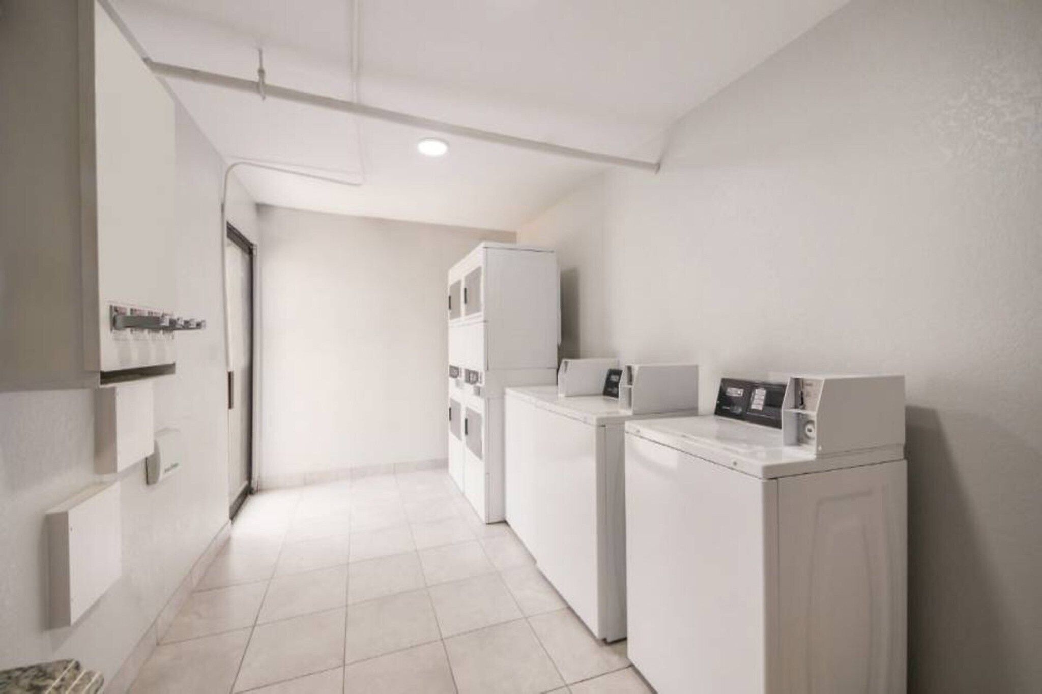A laundry room with a washing machine, dryer, and stacked cabinets.