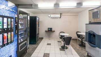 A clean, modern room with a vending machine, a small table with a computer, and seating.
