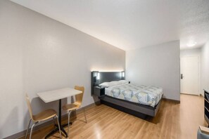Une chambre à coucher comprenant un lit, une table de chevet, une chaise et un bureau.