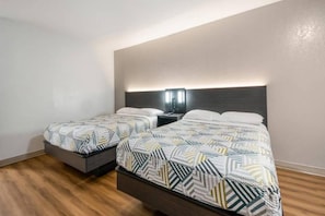 Une chambre d’hôtel avec deux lits, une table de chevet avec une lampe et un plancher en bois.