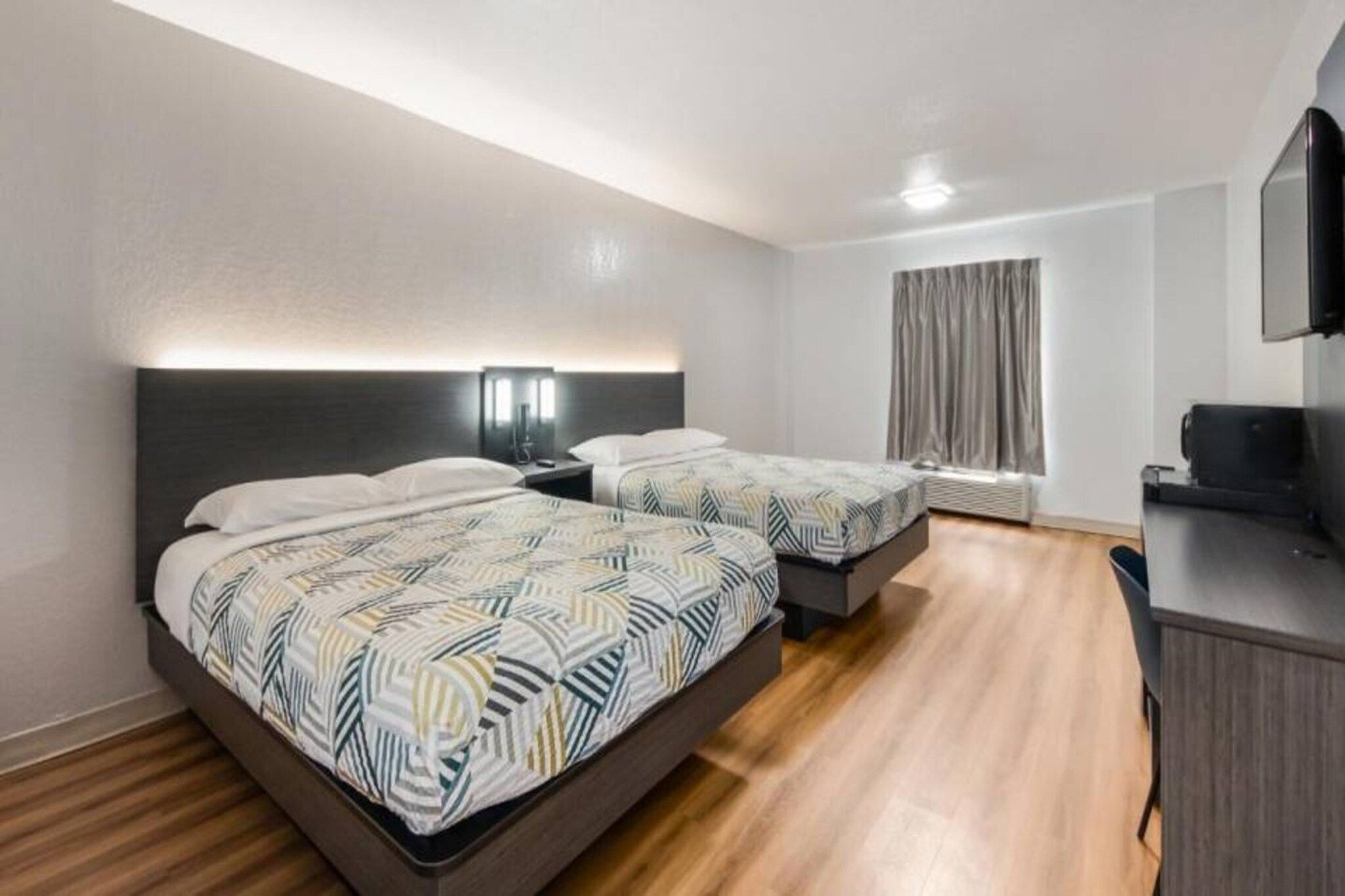 Une chambre d’hôtel avec deux lits, un bureau et une télévision.