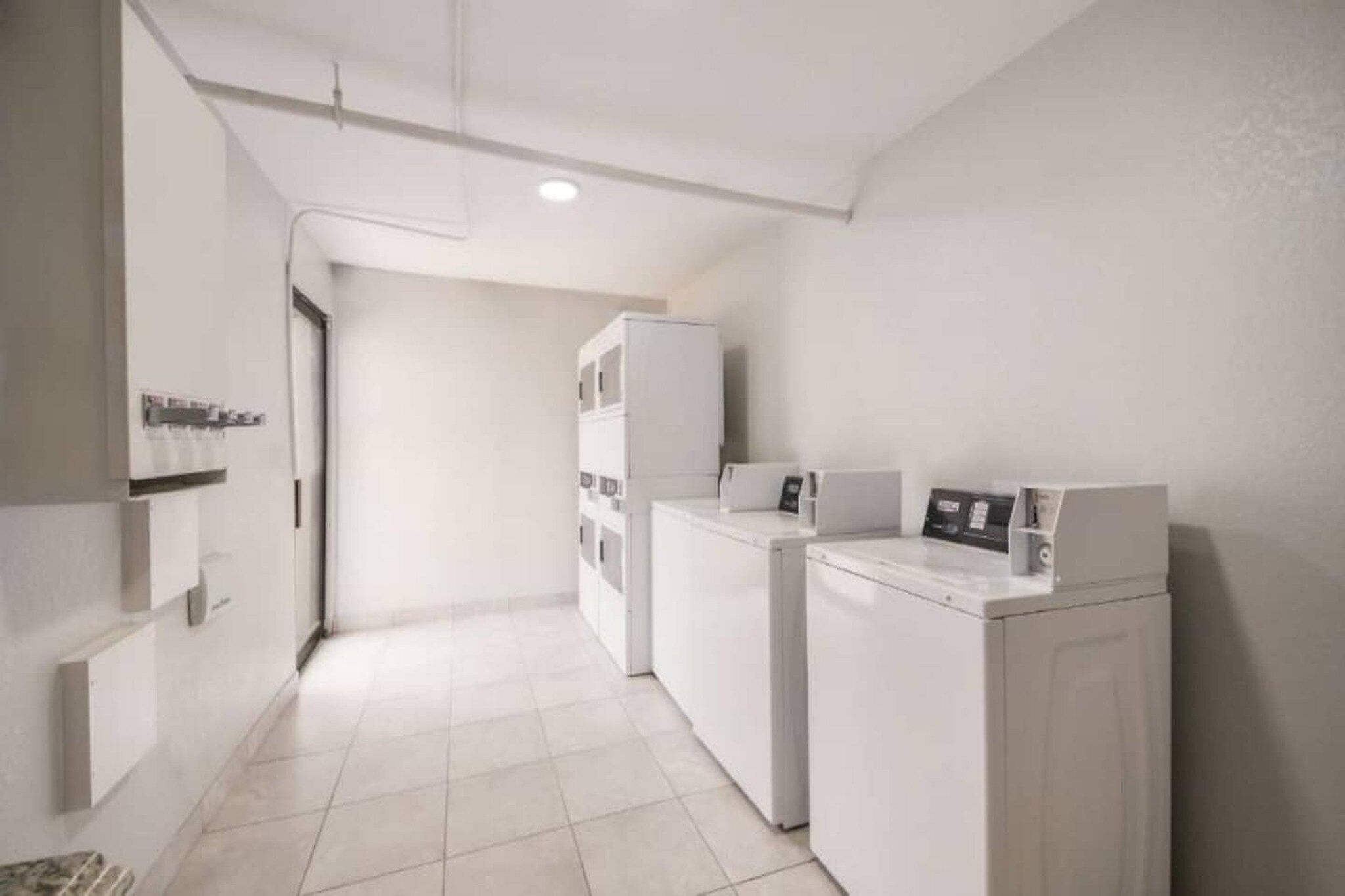 Un cuarto de lavado con dos lavadoras, una secadora y un refrigerador pequeño.