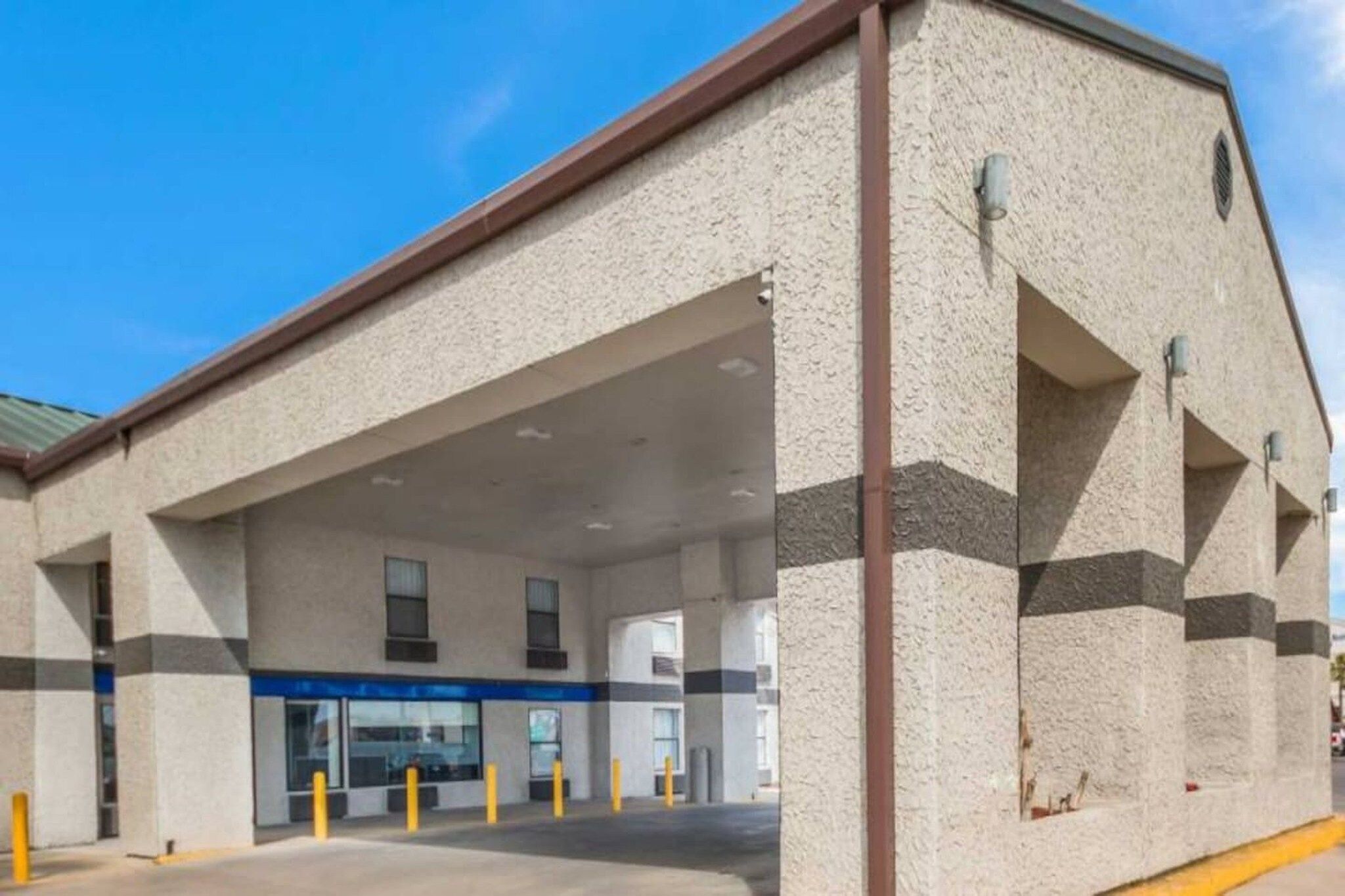 A building with a flat facade, large windows, and a covered entrance area.