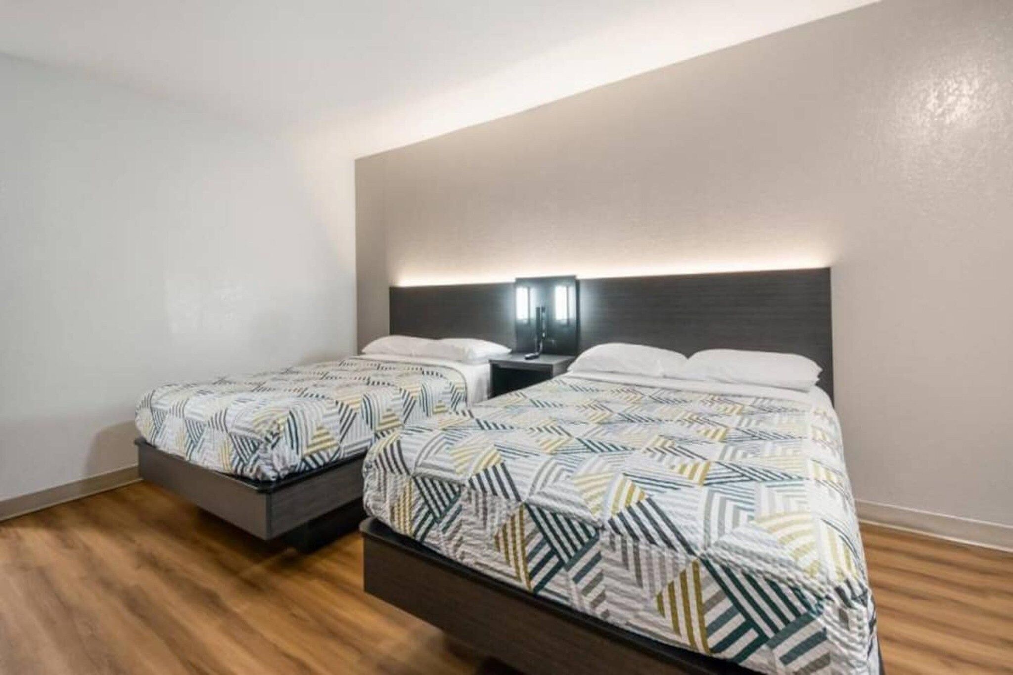 Une chambre d’hôtel avec deux lits, une table de chevet avec une lampe et un plancher en bois.