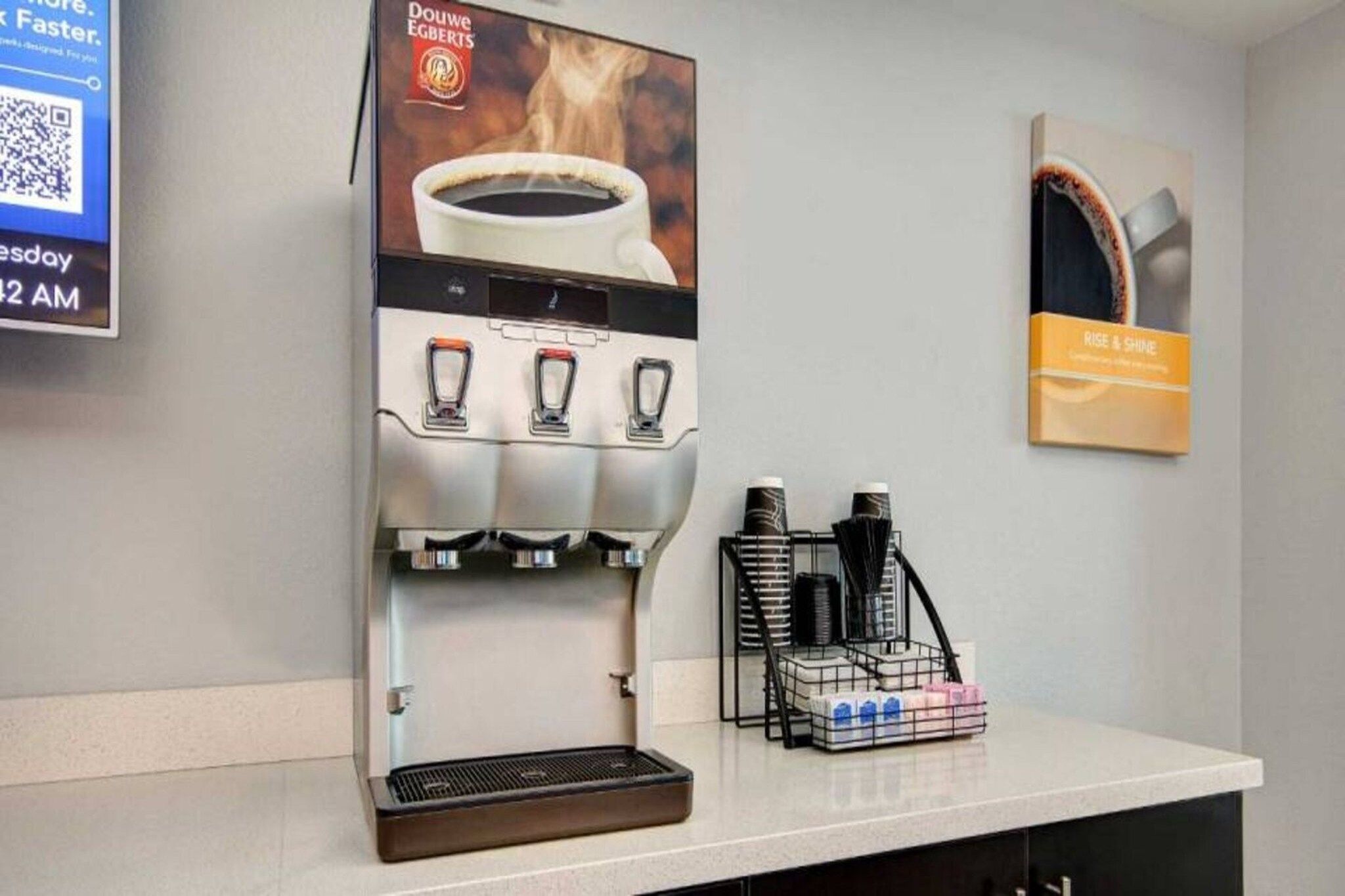 A coffee machine with a cup of coffee and a poster on the wall.